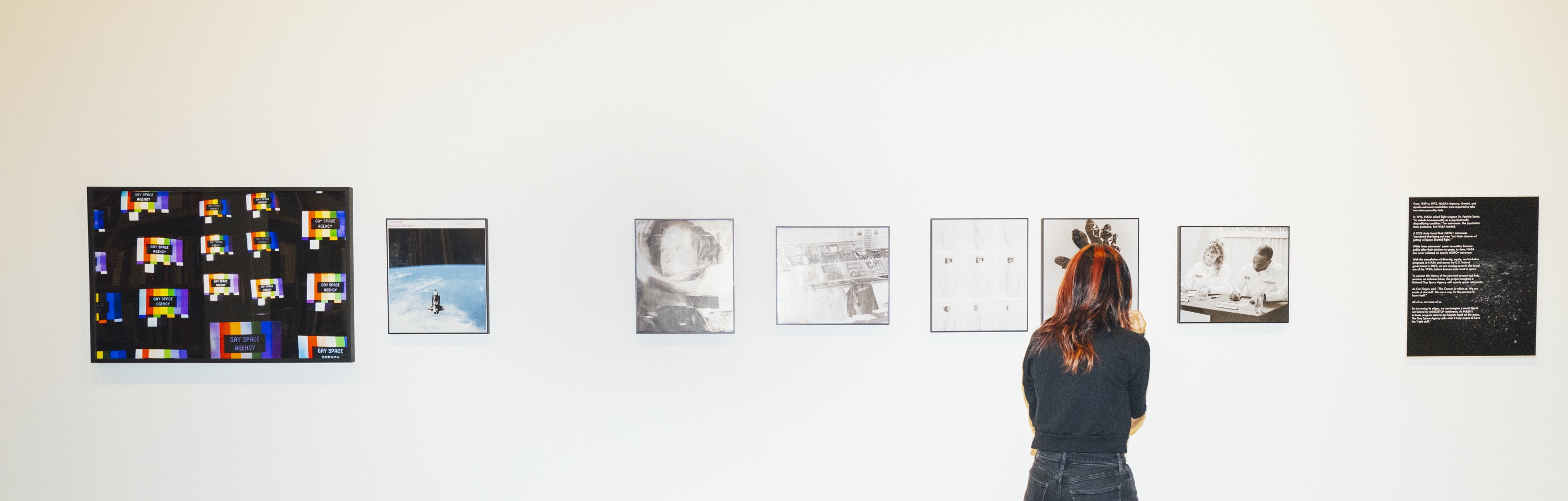 Person views framed photographs on wall