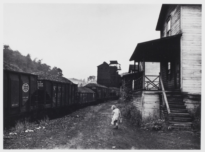 Coal miner's child taking home kerosene for lamps. Company houses, coal tipple in background, Pursglove, Scotts Run, West Virginia