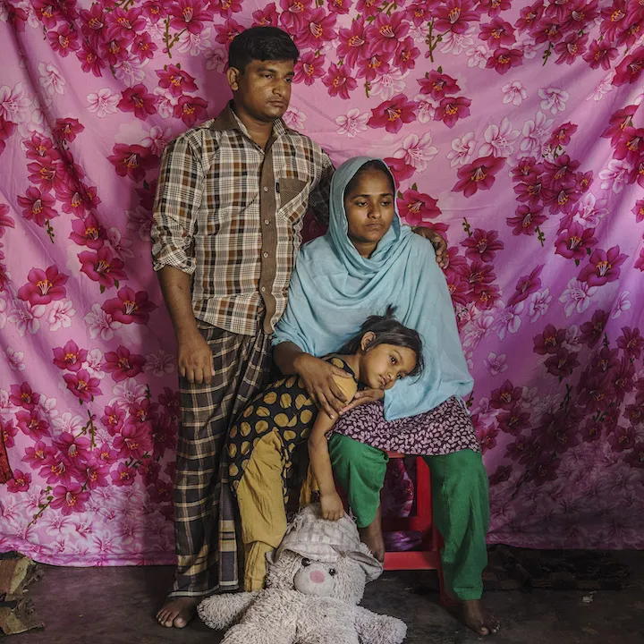 Family sitting in front of floral pink and red backdrop